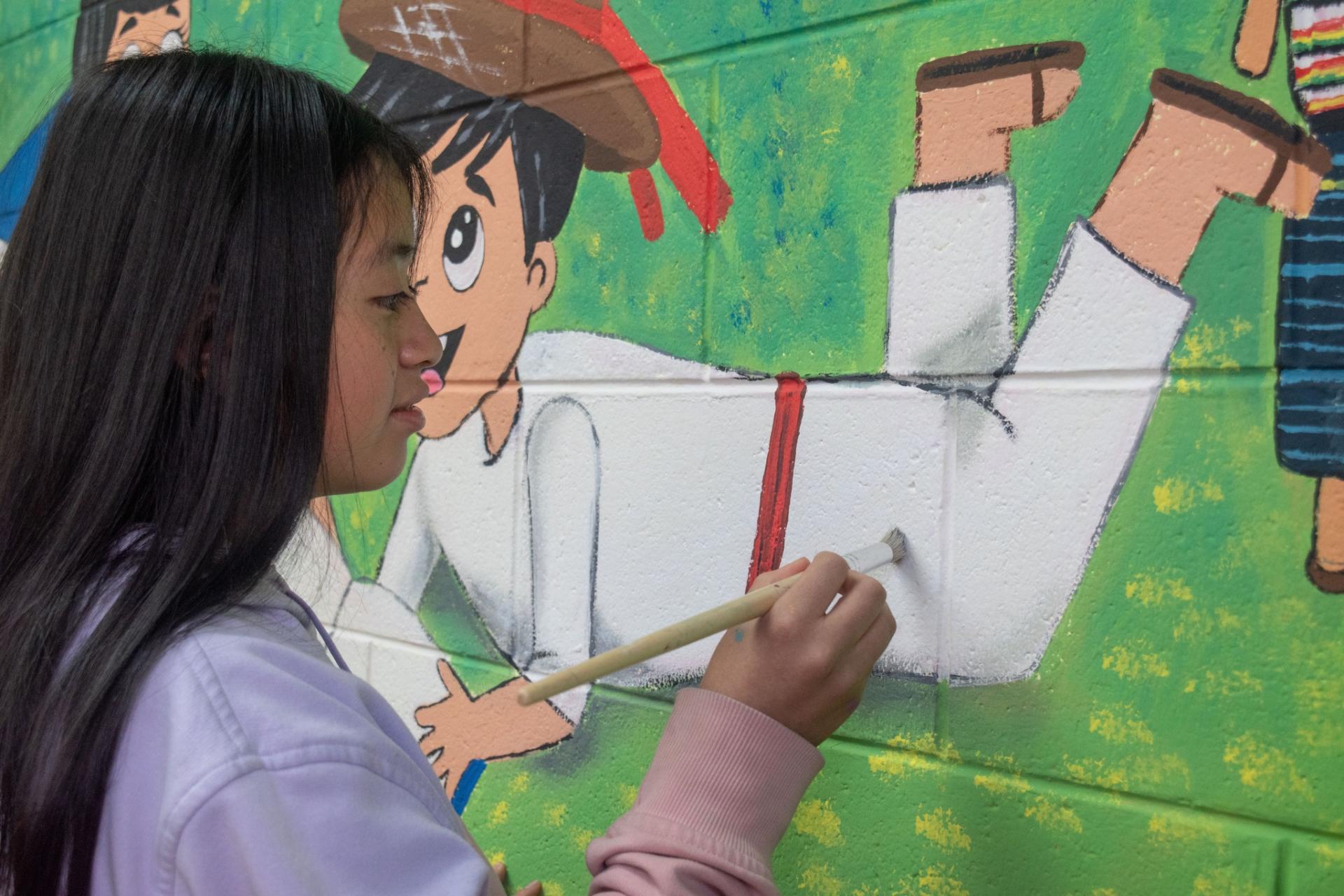 Un muralista pintando un diseño en una pared.